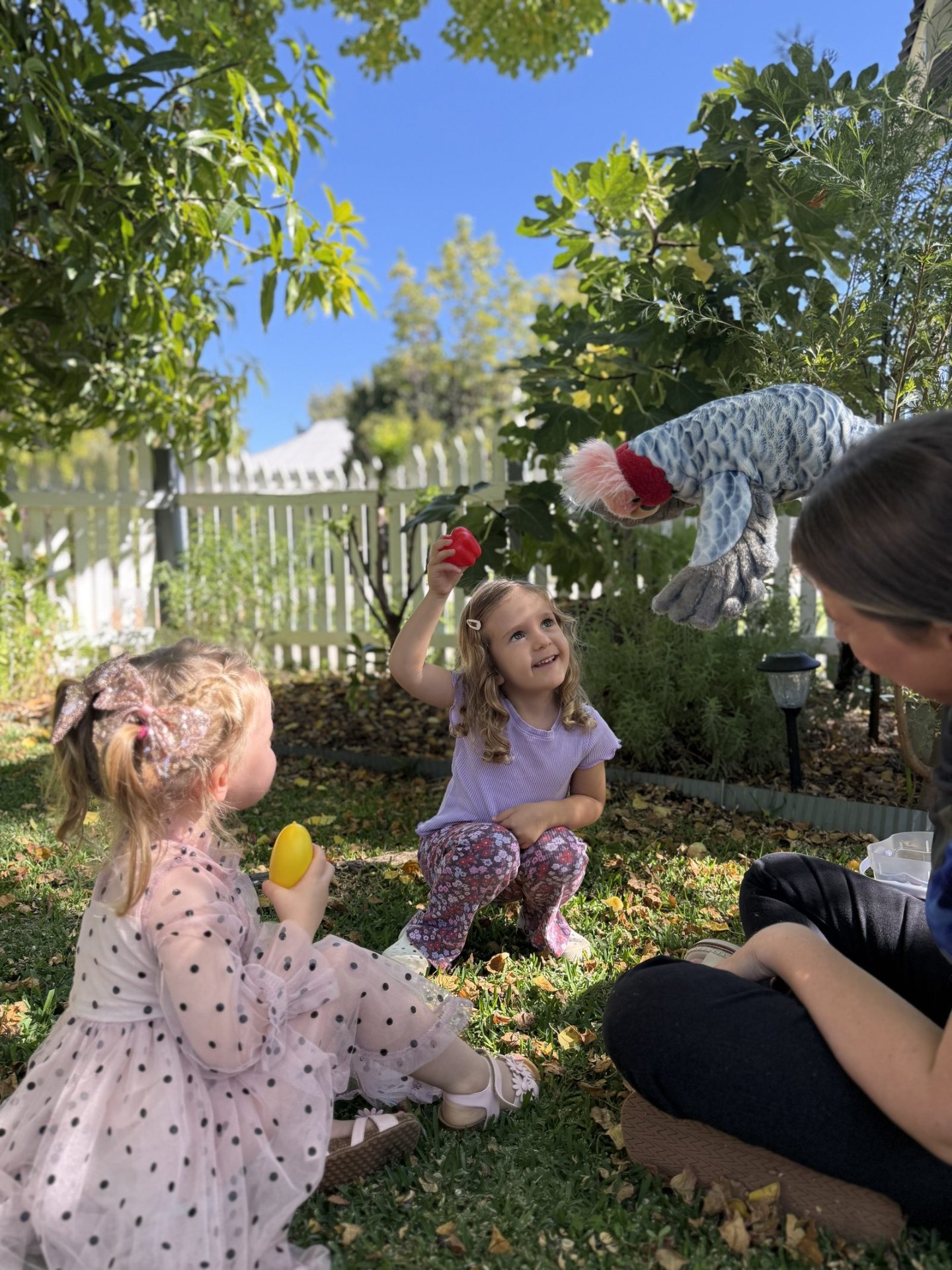 A Blossom and Bloom Speech Pathologist using a puppet with two children during an outdoor session